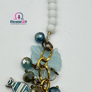 Close-up of handmade beach necklace with Czech glass beads and resin leaves and white natural stone beads.
