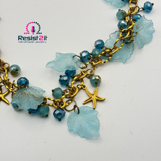 Jewelry with blue beads and gold chain on a white background, featuring Resist2it logo.
