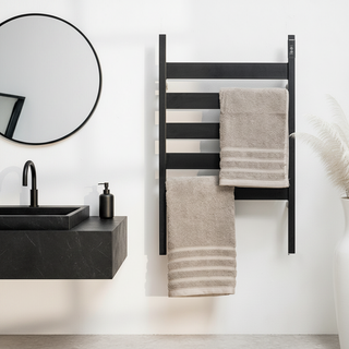 Bathroom with black AUREA™ Electric Heated Towel Rail – 5 Bars  towel rack holding beige towels, round mirror, and black sink.