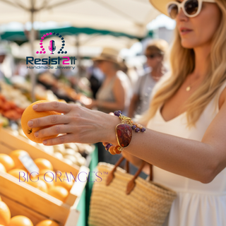 Woman wearing the BIG ORANGES™ handmade bracelet shopping at a French market, holding an orange.