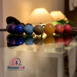 Chakra Explosion rainbow bracelet reflected on glass surface in warm ambient lighting