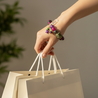 Close-up of a woman's hand wearing the Chunky™ handmade with white crystal and a selection of gemstone beads, carrying shopping bags by Resist2it 