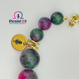 Bracelet with multicolored beads and a gold charm on a white background, featuring 'Resist2it Handmade Jewelry' logo.
