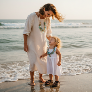 Mom and child standing on a beach with ocean waves bot wearing Sea Breeze Treasures™ necklace