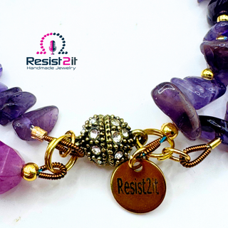 Violet Duality Purple beaded bracelet with gold accents and 'Resist2it' tag and a rhinestone magnetic clasp 