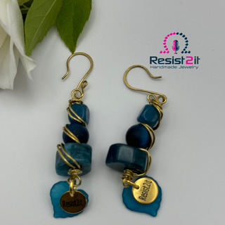 Artisan blue gemstone earrings displayed on neutral background with Resist2it charm