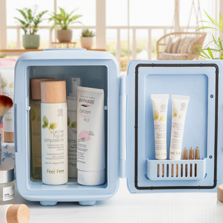 Small blue FRESCA™ refrigerator with skincare products inside, set against a blurred indoor background.