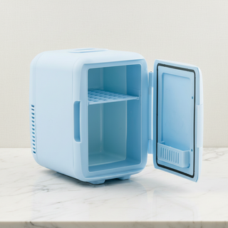 Small blue FRESCA™ Beauty Fridge with open door on a light surface