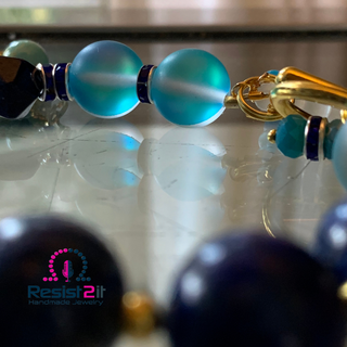 Close-up of a beaded bracelet with blue beads on a reflective surface.