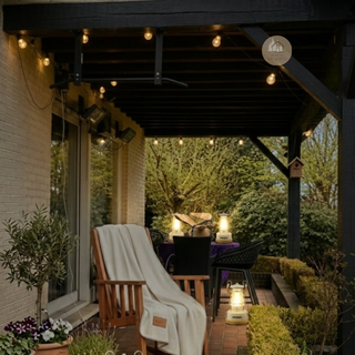 Outdoor porch with wooden chair with The Soft Pause™ throw, a table, and different Golden Hour Led Lantern Sets™ under a covered area.