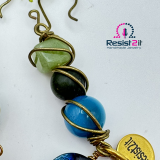 Detail of the gemstones of the Hooked!™ earrings by Resist2it, showing peridot, jade and agate beads, wire wrapped