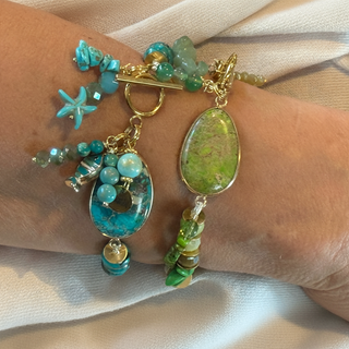 Close-up of a wrist wearing two colorful bracelets with turquoise and green stones.