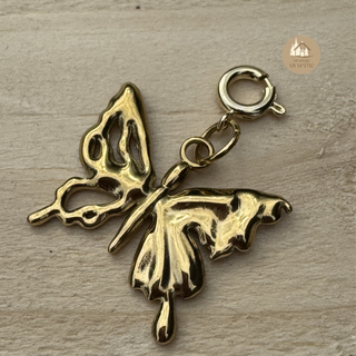 Gold butterfly-shaped charm on a wooden surface