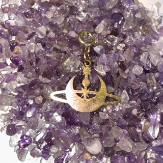 Jules' Inner Orbit Gold charm with moon and star design on a bed of purple amethyst chips