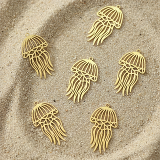 Five gold Jules' Cute Jellyfish charms™ on a sandy surface
