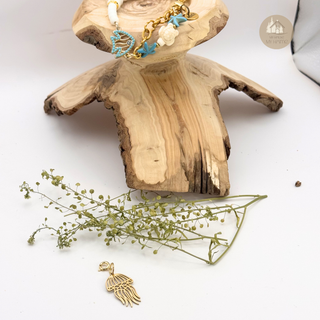 Sealife™ bracelet with charms on a piece of wood, accompanied by Jules' Cute Jellyfish™ Charm and greenery on a white background.