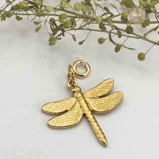 Jules' Magical Dragonfly gold charm on a white background with greenery