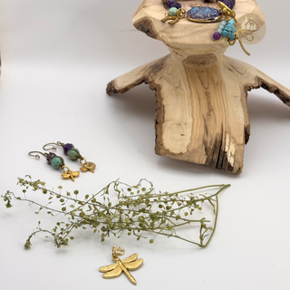 DRAGONFLY™ jewelry set including earrings and a bracelet on a wooden stand with the Jules' Magical Dragonfly Charm in the front