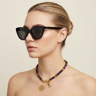 Woman wearing sunglasses and the  short colorful SOLSTICE™ Necklace with tiger eye beads in different colors and a sun gold pendant 