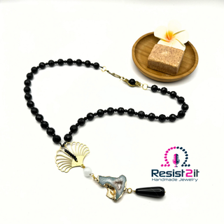 Black beaded necklace with gold and white accents on a white background, featuring 'Resist2it Handmade Jewelry' logo.