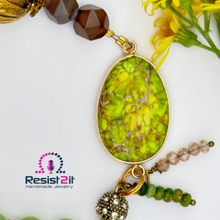 Jewelry with a green pendant and brown beads on a white background, featuring Resist2it Handmade Jewelry logo.