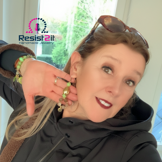 Woman wearing beaded earrings and bracelet, with 'Resist2it' logo.
Close up vintage tulip gold earrings natural stone jewelry
