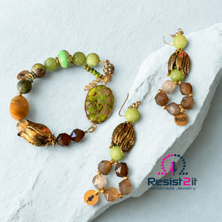 Jewelry set with beads and gold accents on a light blue stone surface, featuring the Resist2it brand.