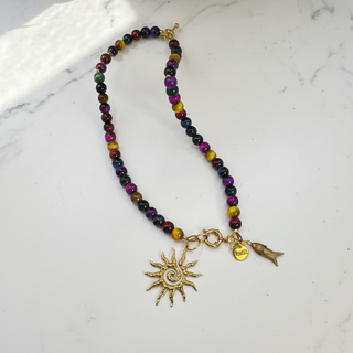 Full view of the SOLSTICE™ Necklace made out of different colors of tiger eye natural stone beads and golden charms in the form of sun,fish and brand Resist2it