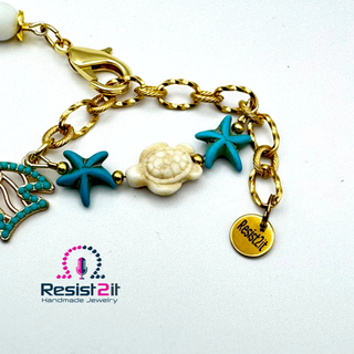 Detail armband goudkleurige ketting met zeesterren, schildpadje en visje.  Handgemaakt Resist2it. 