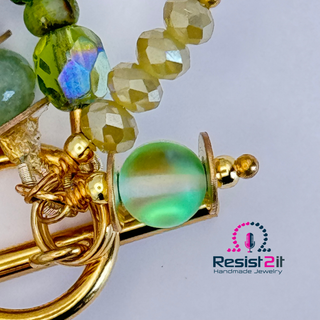 Close-up of a gold and green beaded Bracelet with golden findings and a 'Resist2it Handmade Jewelry' logo.