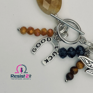 Keychain with 'Good Luck' charm, beads, and other charms on a white background with Resist2it logo.