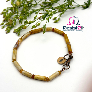 Beaded bracelet with a lock charm on a white background with greenery