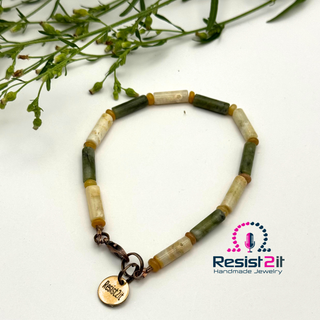 Handcrafted men's bracelet with beige/green tube beads, a copper clasp, and a charm with a Resist2it