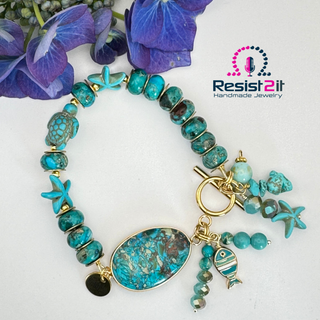 Turquoise beaded bracelet with charms on a white background, featuring 'Resist2it Handmade Jewelry' logo.