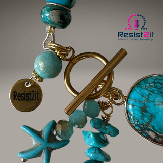 Turquoise beaded bracelet detail with gold toggle clasp and 'Resist2it' tag on a beige background