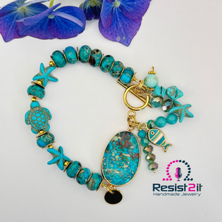 Turquoise beaded bracelet with gold accents and charms on a white background, featuring the Resist2it brand.