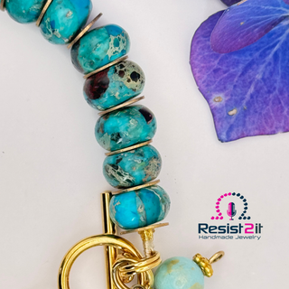 Close-up of chrysocolla and turquoise beads in handmade coastal bracelet, featuring Resist2it logo