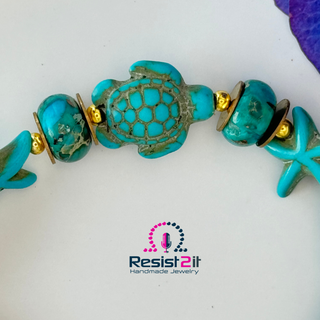 Turquoise beaded bracelet with turtle design on a white background, featuring Resist2it logo.