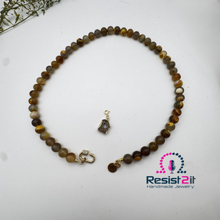 UNSPOKEN™ Tiger Skin Agate Necklace with the detached agate slice pendant, featuring the Resist2it Handmade Jewelry logo