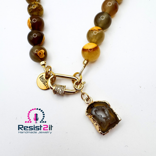 Detail of the UNSPOKEN™ Tiger Skin Agate Necklace with detachable pendant showing clasp, pendant, and Resist2it charm