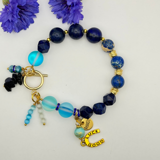 Handmade beaded equestrian bracelet with blue beads and gold charms and Resist2it branding.