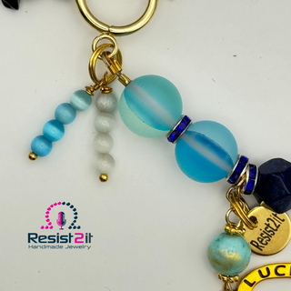 Detail of a beaded bracelet with 'Resist2it' charm and 'Good Luck' horseshoe charm 