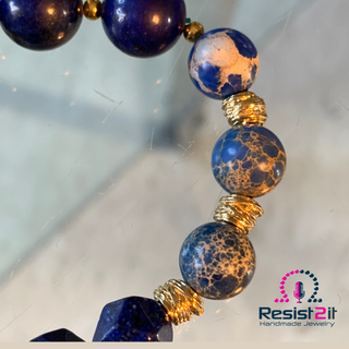 Close-up of a bracelet with blue and gold beads on a reflective surface
