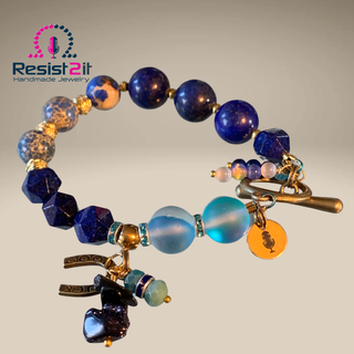 Colorful beaded bracelet with charms on a neutral background, featuring the Resist2it brand.
