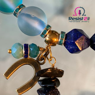 Colorful beaded bracelet with a gold horse shoe charm on a reflective surface