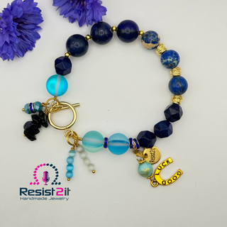 Handmade beaded equestrian bracelet with blue beads and gold charms and Resist2it branding.