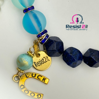 Detail of a beaded bracelet with 'Resist2it' charm and 'Good Luck' horseshoe charm 
