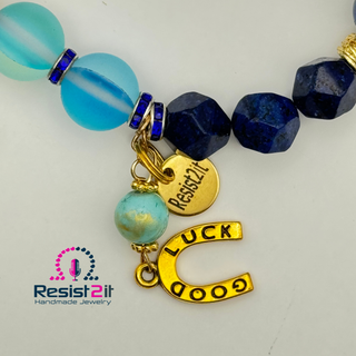 Detail of a beaded bracelet with 'Resist2it' charm and 'Good Luck' horseshoe charm 