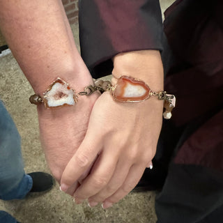 Two hands holding each other and wearing handmade equestrian bracelet with natural stone
